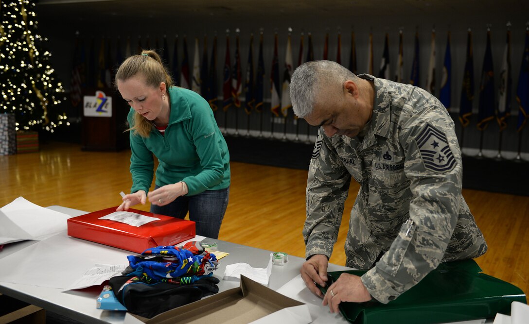 Command Chief Master Sgt. Raul Villarreal Jr., 14th Flying Training Wing command chief, and Katie Steinback, spouse of Senior Master Sgt. Wade Steinback, 14th Flying Training Wing Staff Agency superintendent, wrap gifts during the Happy Irby Fund Shop and Wrap at the Club Dec. 12, 2018, on Columbus Air Force Base, Mississippi. (U.S. Air Force photo by Airman Hannah Bean)