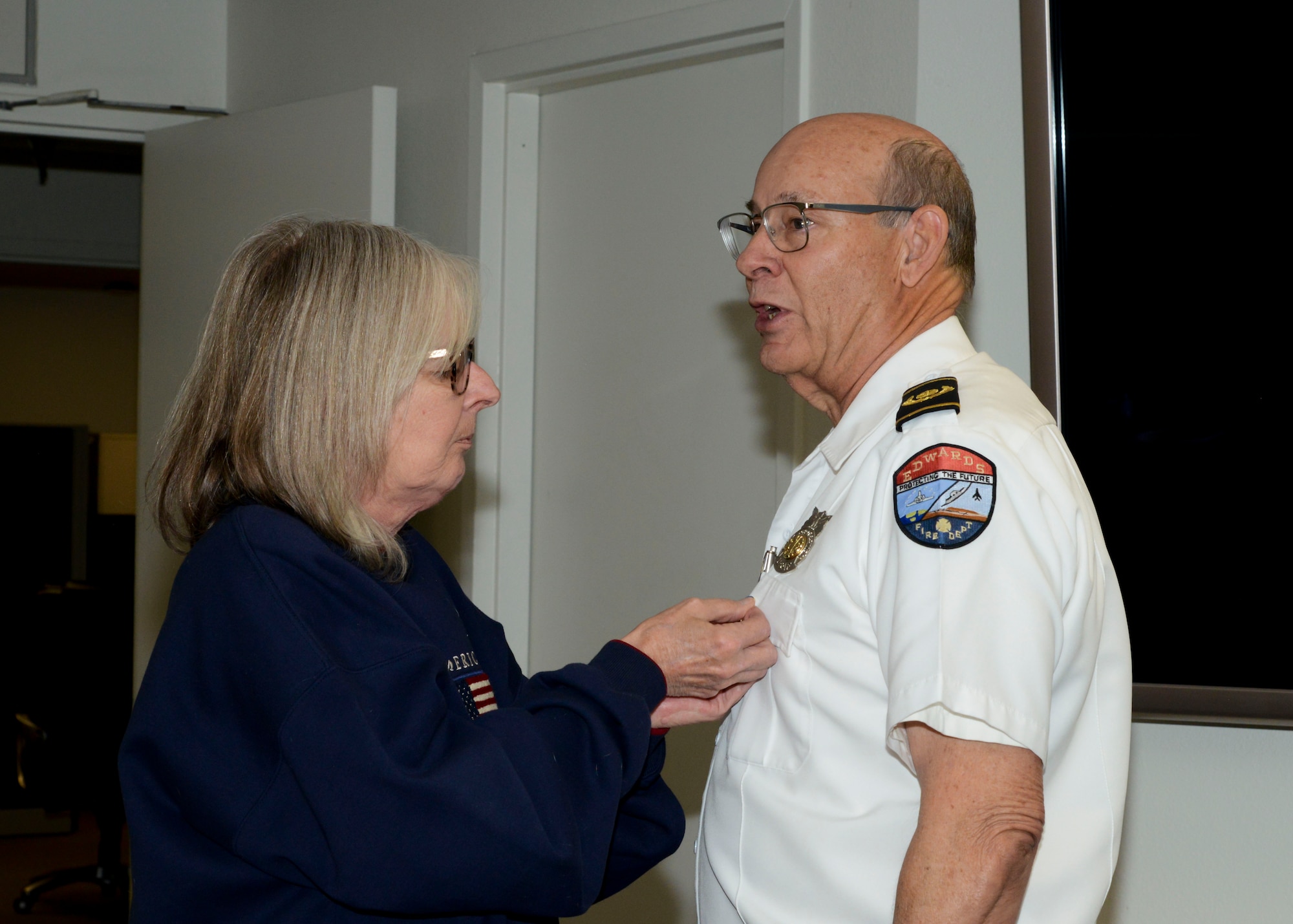 Tammy Hurles, wife of Retiring Fire Chief, Michael Hurles, pins a retirement pin during a retirement ceremony at Edwards Air Force Base, California, Dec. 14. Hurles retired after 42 years of service. (U.S. Air Force photo by Giancarlo Casem)