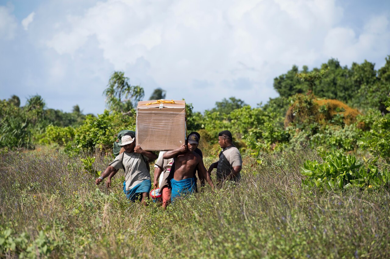 Residents carry a box of humanitarian supplies on their shoulders.