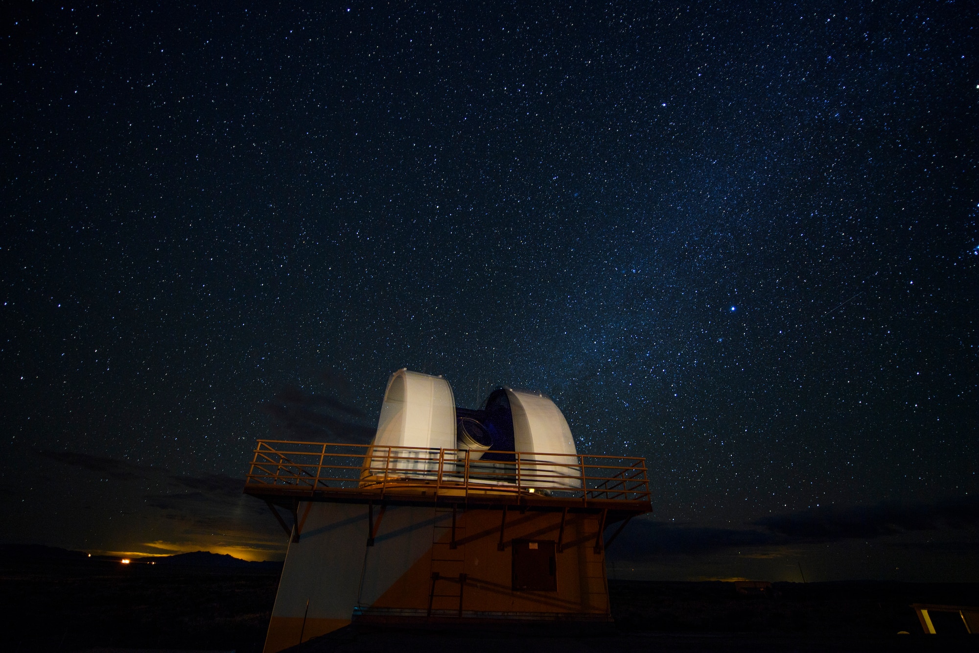 A telescope sits underneath the Milky Way Galaxy.