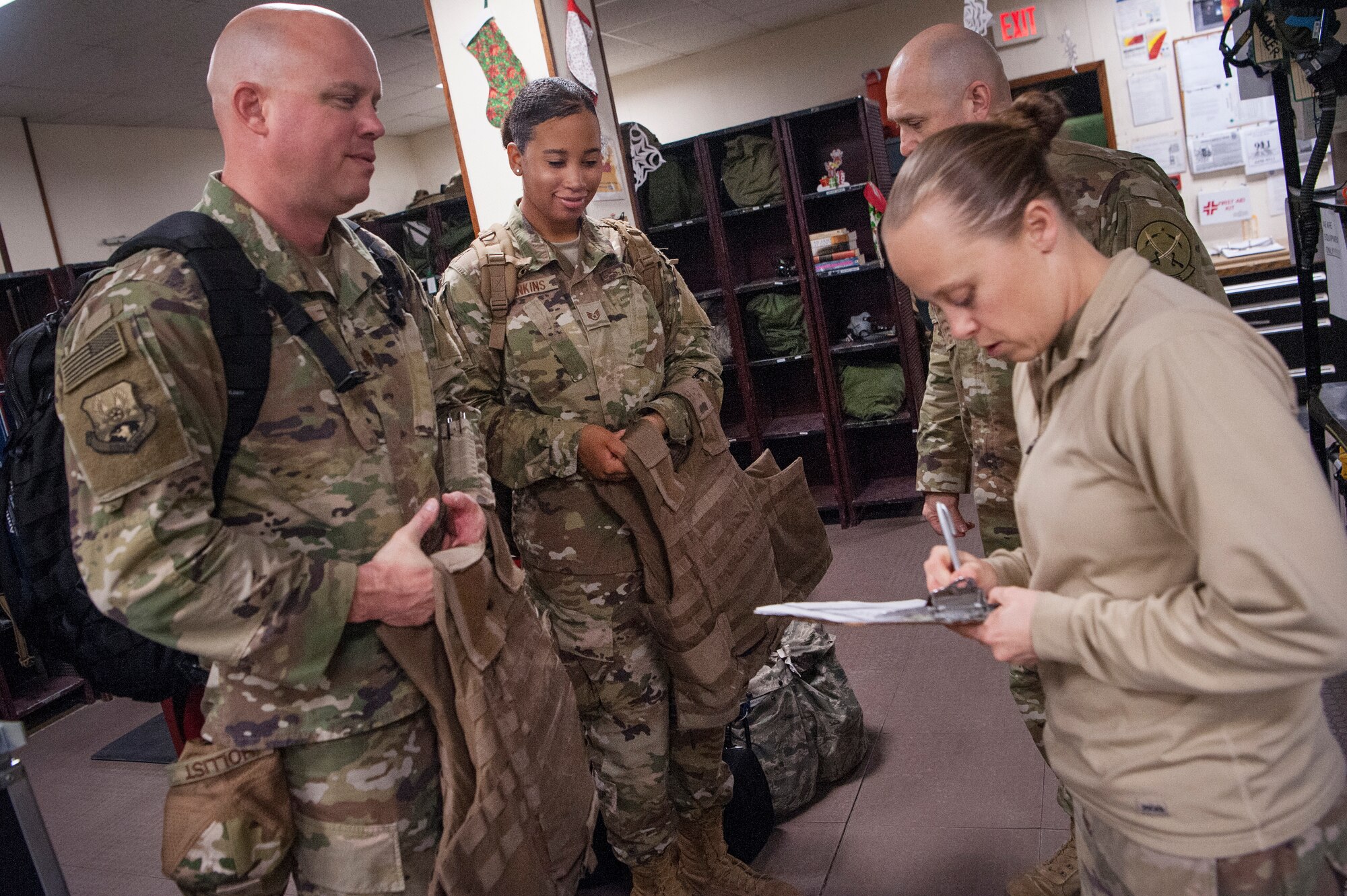 Tech. Sgt. Ashley Solum, right, 379th Expeditionary Operations Support Squadron aircrew flight equipment (AFE) technician, issues AFE gear to Chaplain (Maj.) Cody Hollist, left, and Staff Sgt. Daneasha Jenkins, center left, both assigned to the 379th Air Expeditionary Wing (AEW) chaplain office, Dec. 15, 2018, at Al Udeid Air Base, Qatar.