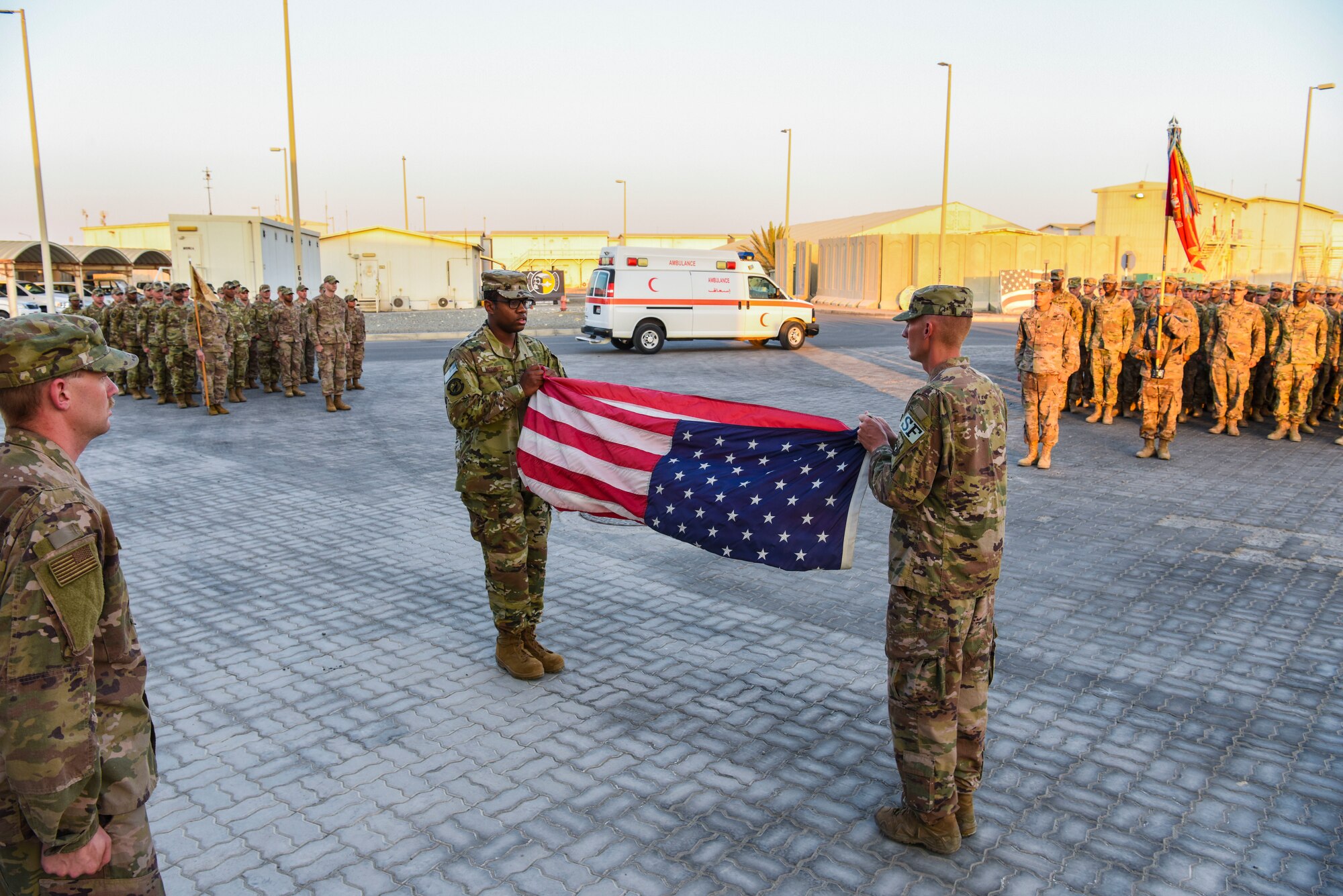 SrA William Rodriguez and SrA Johnathan Coble, 380th Expeditionary Security Forces Squadron, begin folding the flag during a monthly retreat ceremony at Al Dhafra Air Base, United Arab Emirates, Dec. 7, 2018.