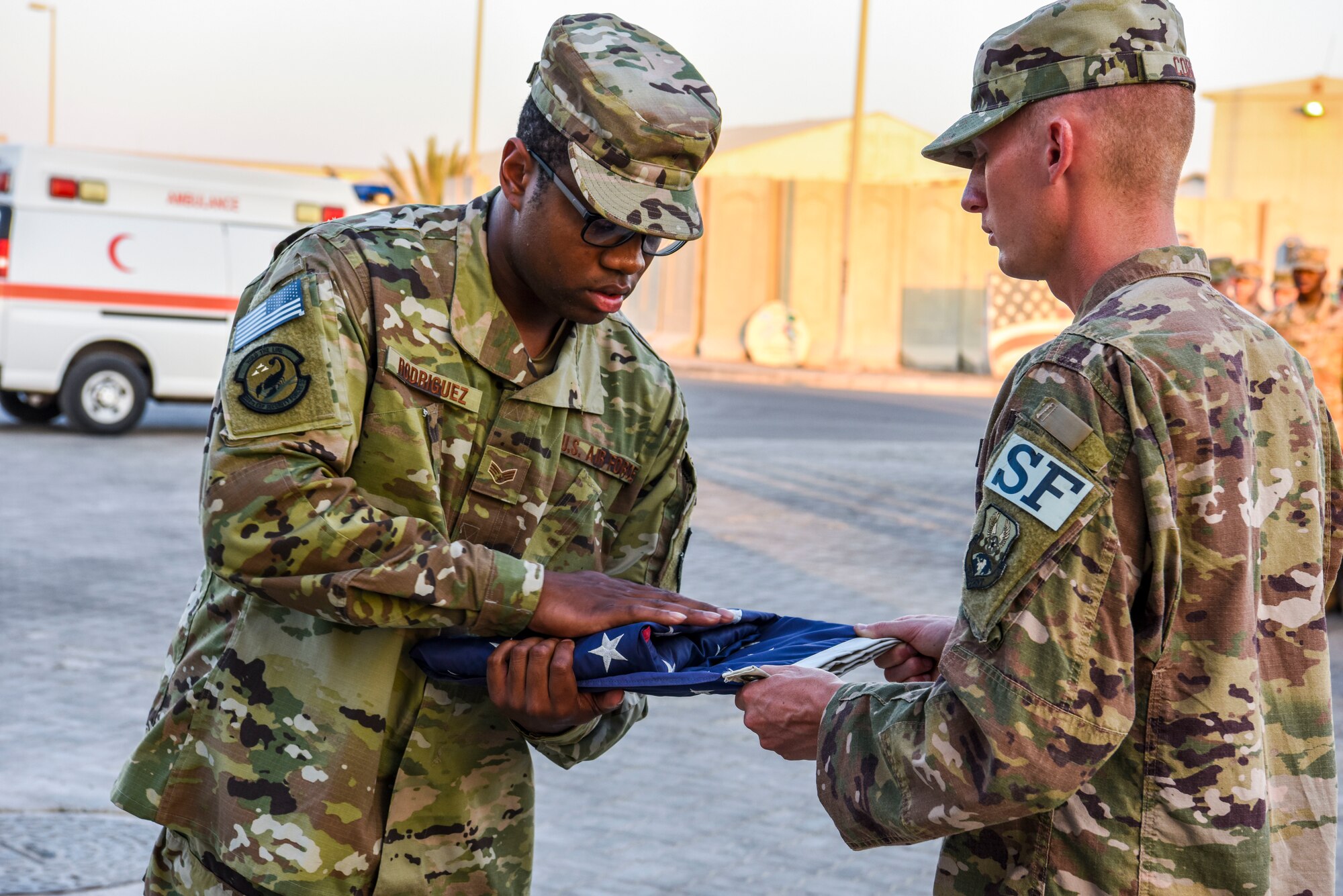 SrA William Rodriguez, 380th Expeditionary Security Forces Squadron, folds the flag held by SrA Johnathan Coble, 380th Expeditionary Security Forces Squadron, during a monthly retreat ceremony at Al Dhafra Air Base, United Arab Emirates, Dec. 7, 2018.