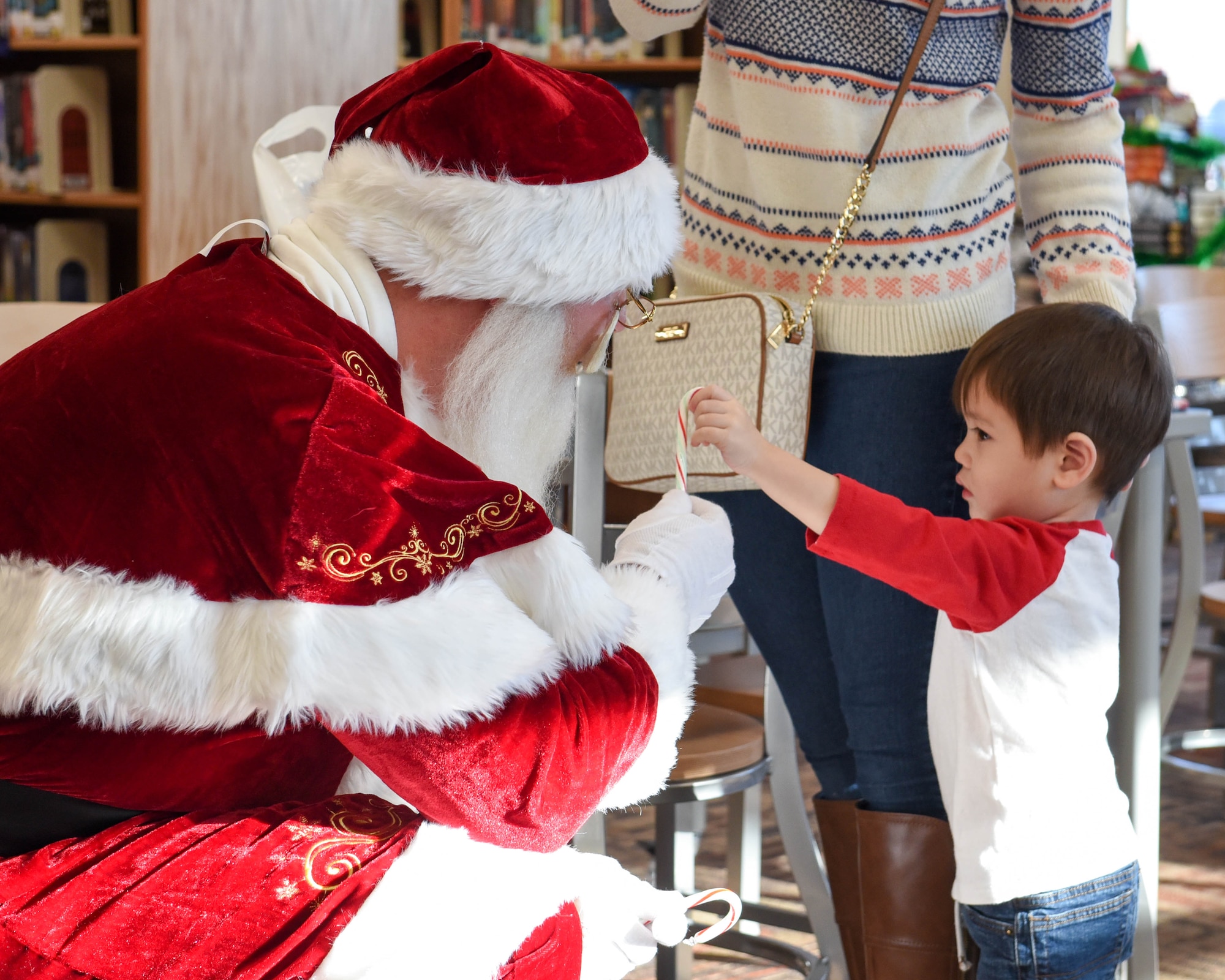 Jolly old Saint Nicholas shares candy canes with children at Ellsworth Air Force Base, S.D., Dec. 13, 2018, during “Santa and Me Story Time.” Saint Nick was escorted by the Ellsworth AFB fire department to Holbrook Library, where he read a holiday book and visited with kids. (U.S. Air Force photo by Airman John Ennis)