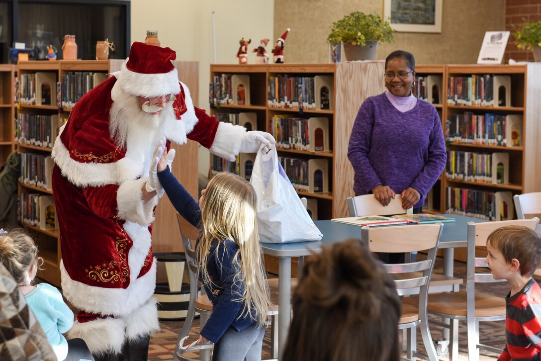 Santa Claus gives out high fives to kids at the Holbrook Library on Ellsworth Air Force Base, S.D., Dec. 13, 2018. Father Christmas visited the base to read a book with the good boys and girls of Ellsworth AFB. (U.S. Air Force photo by Airman John Ennis)