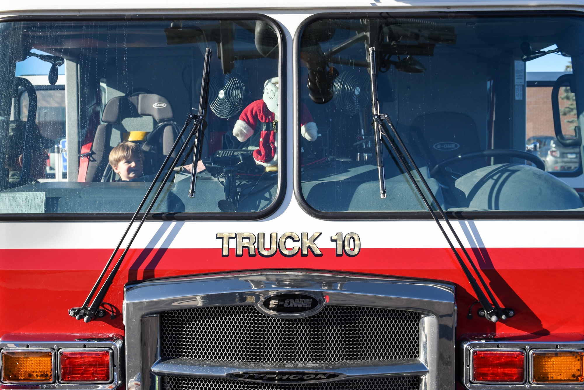 A child at Ellsworth Air Force Base, S.D., is given the chance sit passenger in a stationary fire truck on Dec. 13, 2018. Following a “Santa and Me Story Time” event at the Holbrook Library, attendees were invited to the parking lot to tour a fire truck and visit with firefighters from the 28th Civil Engineer Squadron Fire Department. (U.S. Air Force photo by Airman John Ennis)