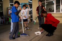 Cpl. Ousman Secka, far right, and Lance Cpl. Dominic A. Ward, center right, help students sweep Dec. 14, 2018 at Ginowan City, Okinawa, Japan. Marines and Sailors with Combat Logistics Battalion 4, Combat Logistics Regiment 3, 3rd Marine Logistics Group, volunteered at the AmerAsian School in Okinawa to help with various beautification projects around the school. The school conducts triannual clean-up projects before each semester. Secka, a native of Louisville, Kentucky, is a motor transportation operator with Transportation Services Company, CLB-4, CLR-3, 3rd MLG. Ward, a native of Wentzville, Missouri, is a landing support specialist with TS Co., CLB-4, CLR-3, 3rd MLG. (U.S. Marine Corps photo by Lance Cpl. Armando Elizalde)