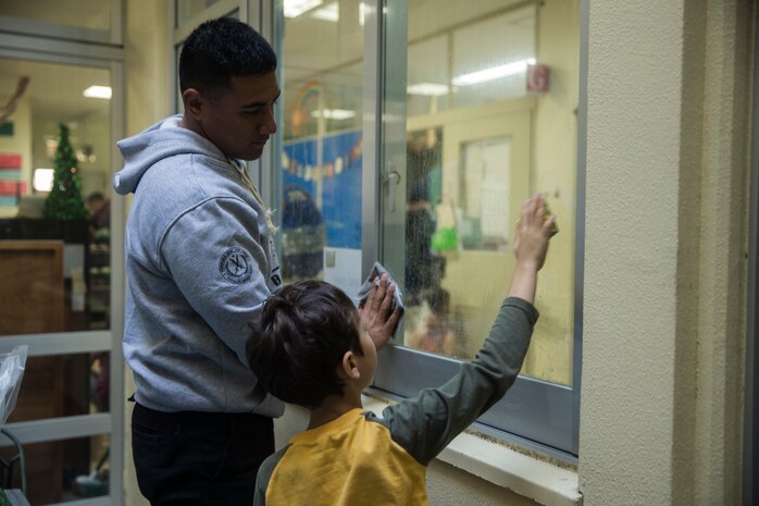 Lance Cpl. Derek S. Pulu helps a student clean a window Dec. 14, 2018 at Ginowan City, Okinawa, Japan. Marines and Sailors with Combat Logistics Battalion 4, Combat Logistics Regiment 3, 3rd Marine Logistics Group, volunteered at the AmerAsian School in Okinawa to help with various beautification projects around the school. The school conducts triannual clean-up projects before each semester. Pulu, a native of American Samoa, is a motor transportation operator with Transportation Service Company, CLB-4, CLR-3, 3rd MLG. (U.S. Marine Corps photo by Lance Cpl. Armando Elizalde)