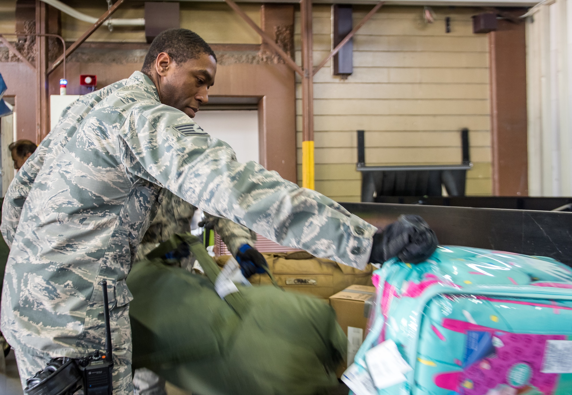 U.S. Air Force Staff Sgt. Troy McCray, 730th Air Mobility Squadron passenger service supervisor, puts luggage on to a baggage carousel