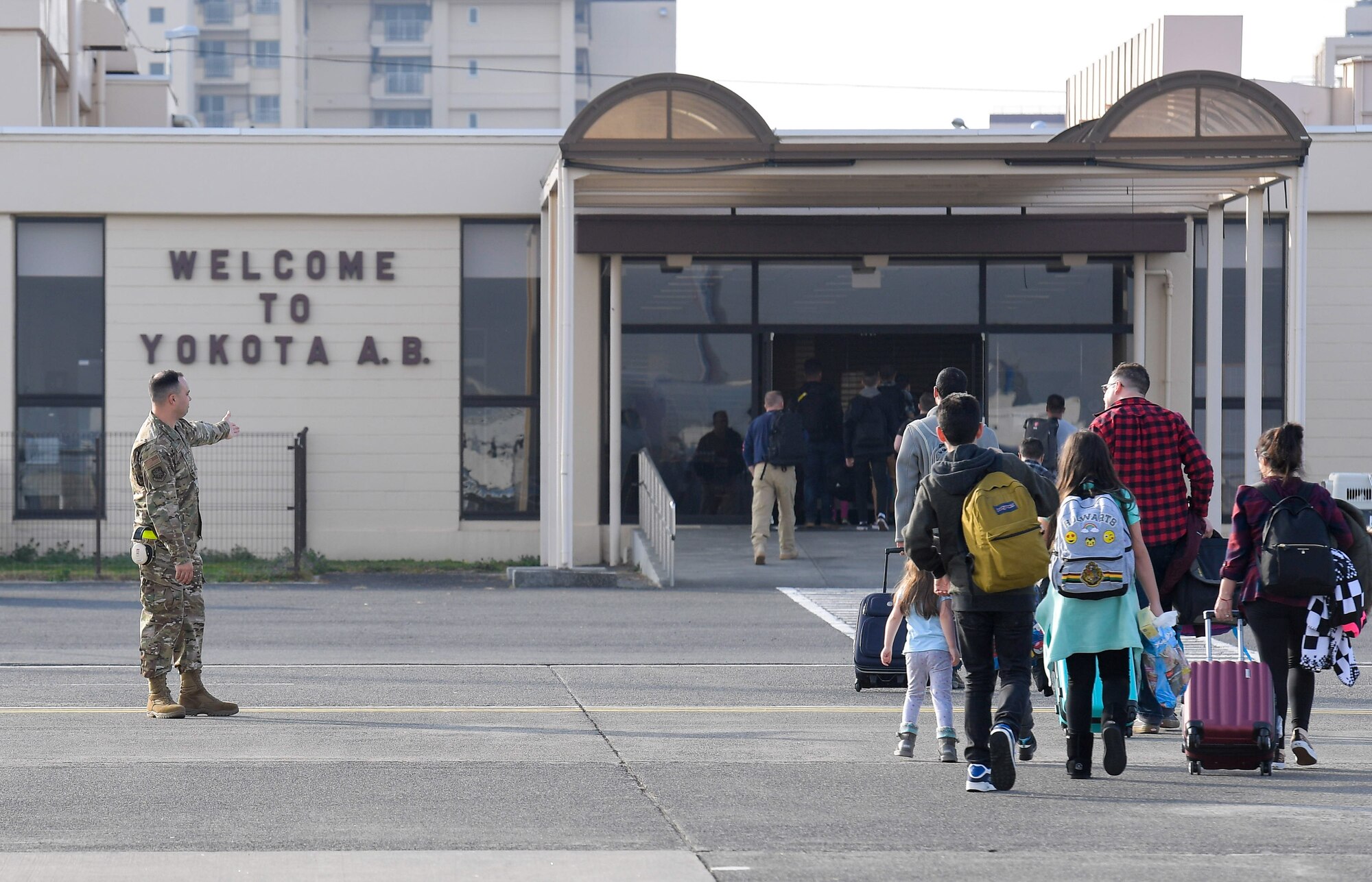 Airman 1st Class Alexander Blankenship, 730th Air Mobility Squadron passenger service agent, guides passengers to the entrance of the Yokota Air Base, Japan, Passenger Terminal