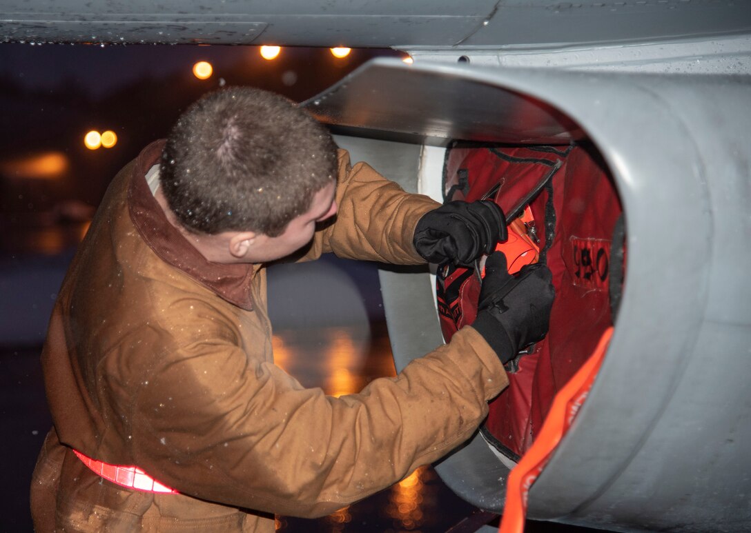 U.S. Air Force Airman 1st Class Avery Fortenbery, a 13th Aircraft Maintenance Unit crew chief, removes covers from a storage pocket on the intake cover of an F-16 Fighting Falcon at Misawa Air Base, Japan, Dec. 11, 2018. This task ensures compliance with aircraft-safe maintenance procedures. (U.S. Air Force photo by Airman 1st Class Genesis Tejada)