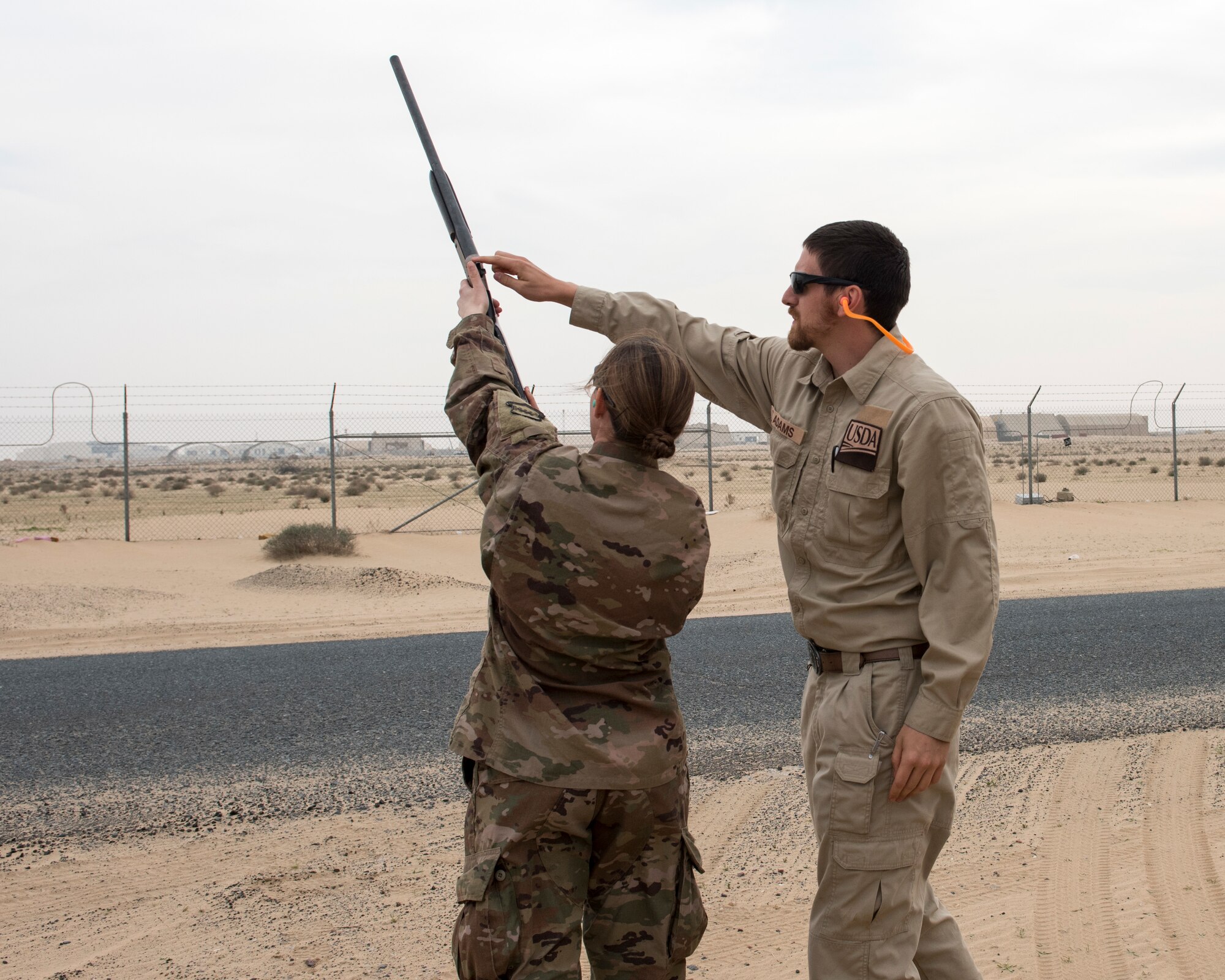 Tyler Adams, United States Department of Agriculture wildlife biologist, shows an Airman where to place her hands while firing a rifle used to shoot pyrtecnics, during the first ever Bird/wildlife Aircraft Strike Hazard program training at an undisclosed location in Southwest Asia, Dec. 3, 2018. Since 2016 nearly three million dollars have been spent on wildlife related damages in the area of responsibility.