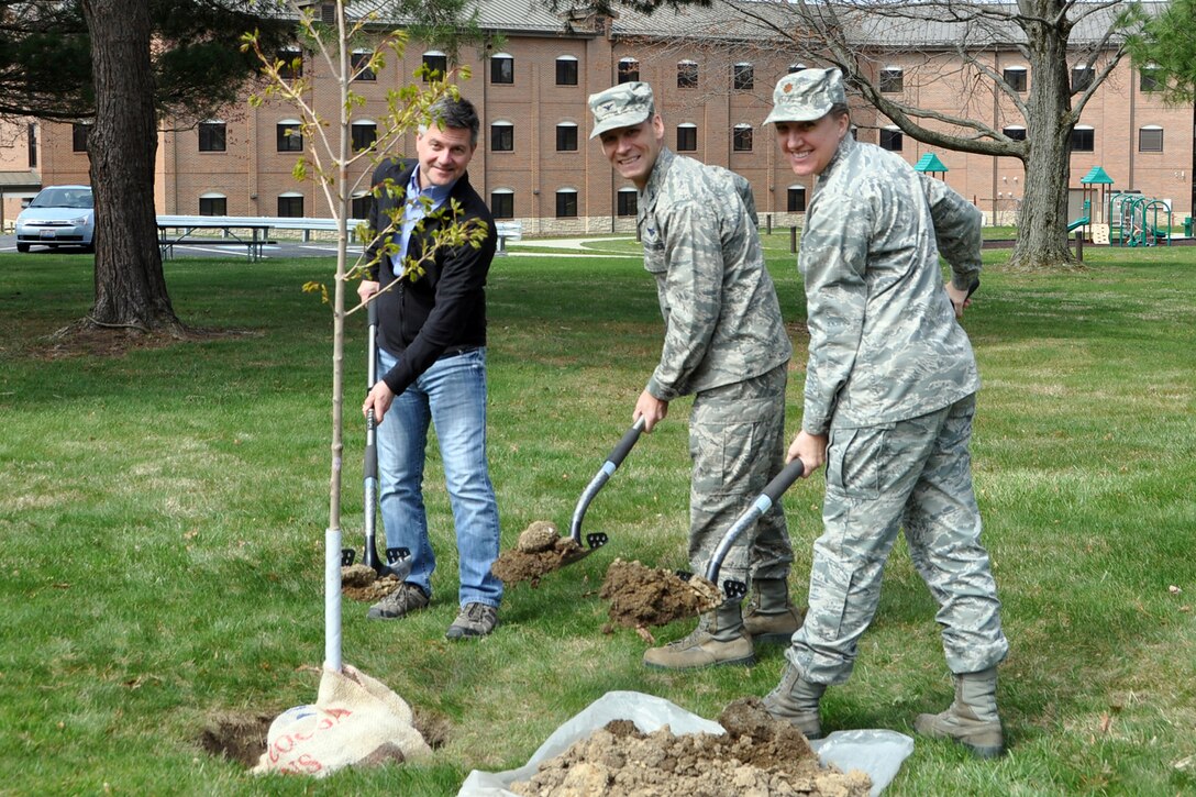 Brady McCann, an environmental engineer here, Col. Joe Janik, vice commander of the 910th Airlift Wing, and Maj. Wendy Strainic, executive officer for the 910th Airlift Wing, pose for a photo while planting a tree on the installation grounds, April 27, 2018.