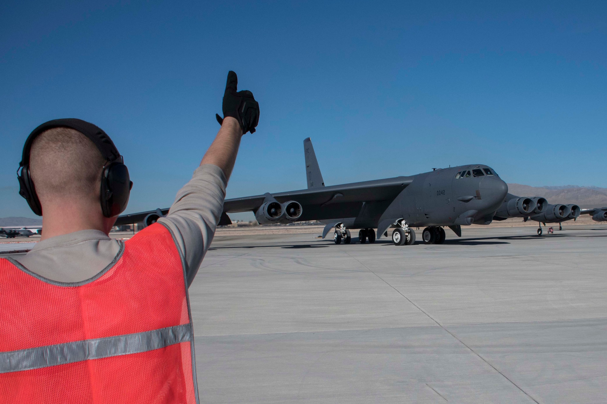 U.S. Air Force Senior Airman Alexander Horrocks, 11th Aircraft Maintenance Unit crew chief, gives a thumbs up to a departing B-52 Stratofortress at Nellis Air Force Base, Nevada, Dec. 11, 2018.  As part of the total force integration model, Horrocks, an active-duty Airman, served alongside Reserve Citizen Airmen maintainers from Barksdale Air Force Base, Louisiana to support the biannual Weapons School Integration exercise.  The Airmen work alongside one another both at Barksdale AFB and in forward locations.  The TFI leverages the continuity and knowledge base of the Air Force Reserve to serve as a force multiplier. (U.S. Air Force photo by Master Sgt. Ted Daigle)