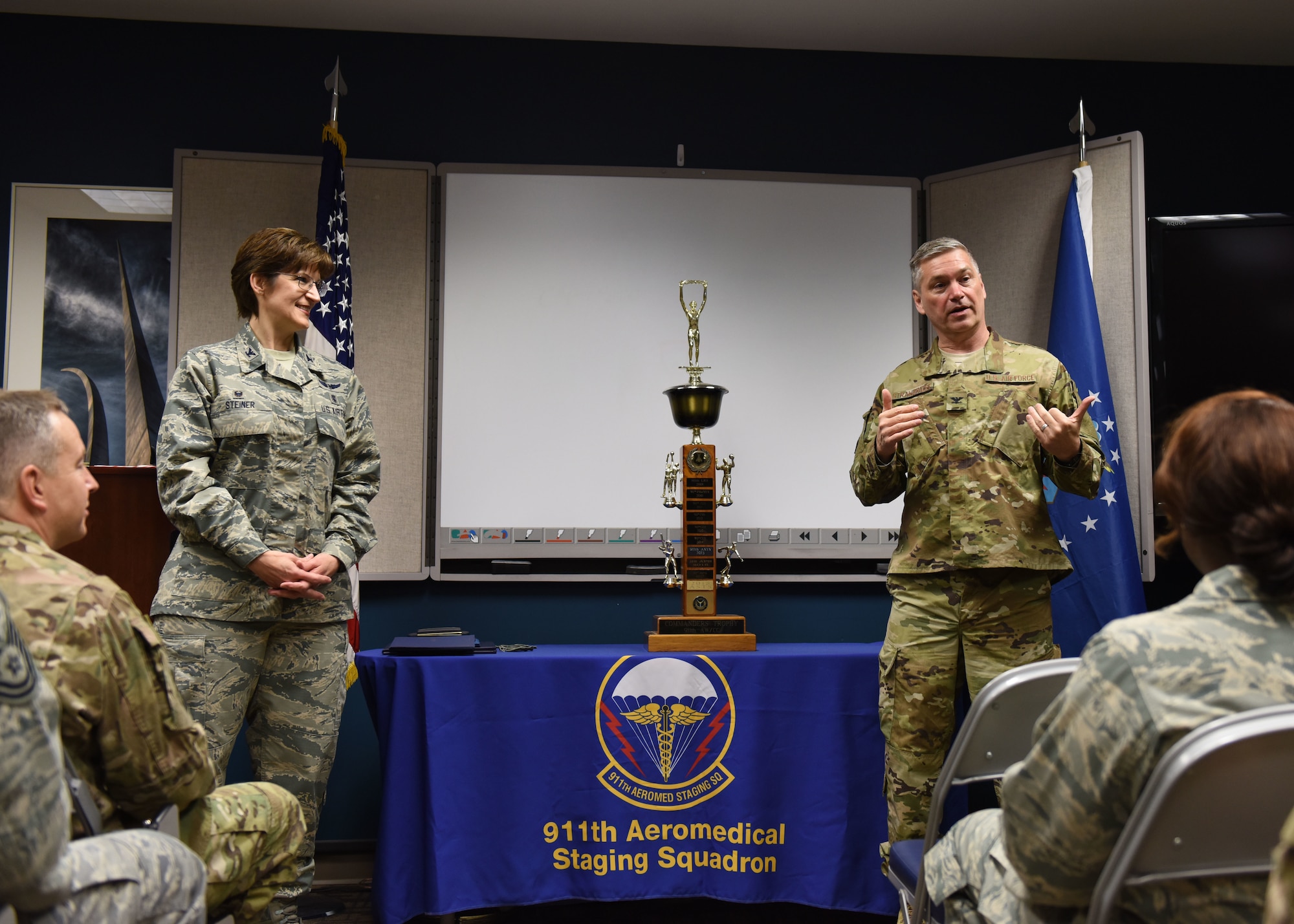 Col. Douglas N. Strawbridge, commander of the 911th Airlift Wing, gives a speech alongside Col. Karen Steiner, commander of the 911th Aeromedical Staging Squadron, and ASTS Airmen at the Pittsburgh International Airport Air Reserve Station, Pennsylvania, December 2, 2018. During his speech, Strawbridge congratulated the squadron on its hard work during the wing intramural sports competition. (U.S. Air Force Photo by Senior Airman Grace Thomson)