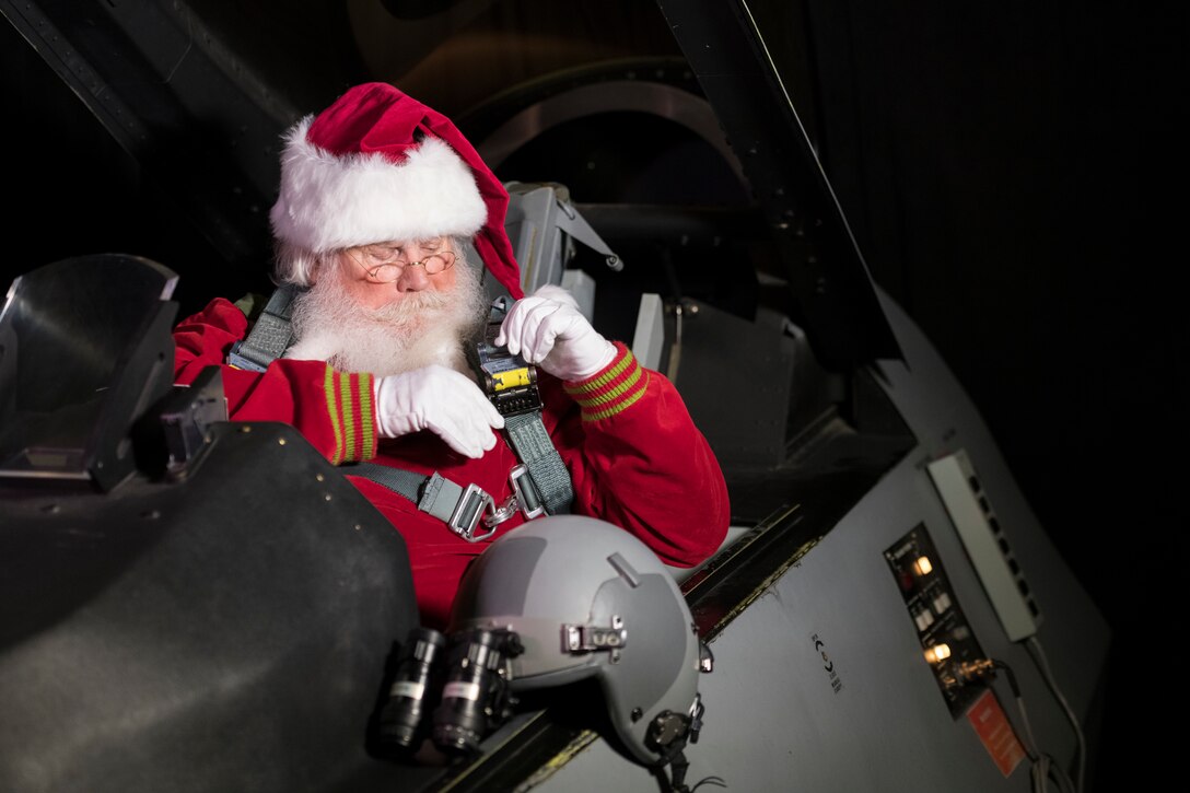 Santa buckles up in the cockpit of a fighter jet.