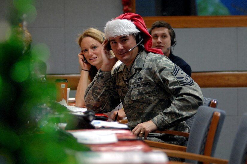 An airman wearing a Santa hat answers phone calls.