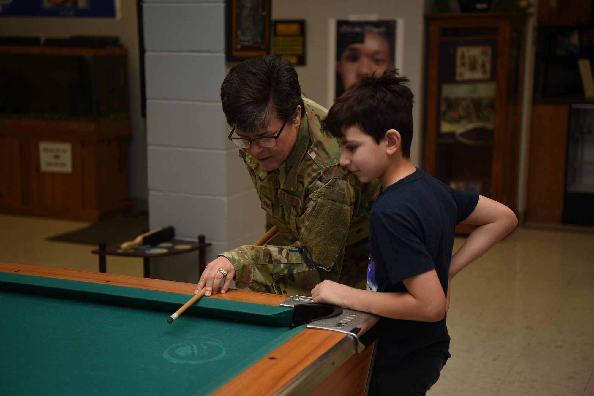 Col. Heather Cook, 319th Mission Support Group commander, and Micah Gass, 9, play pool together in the Youth Center, December 12, 2018, on Grand Forks Air Force Base, North Dakota. Cook discussed winter safety with Gass, ensuring he knew how he was going to stay vigilant and safe during the upcoming winter months. (U.S. Air Force photo by Airman 1st Class Melody Wolff)