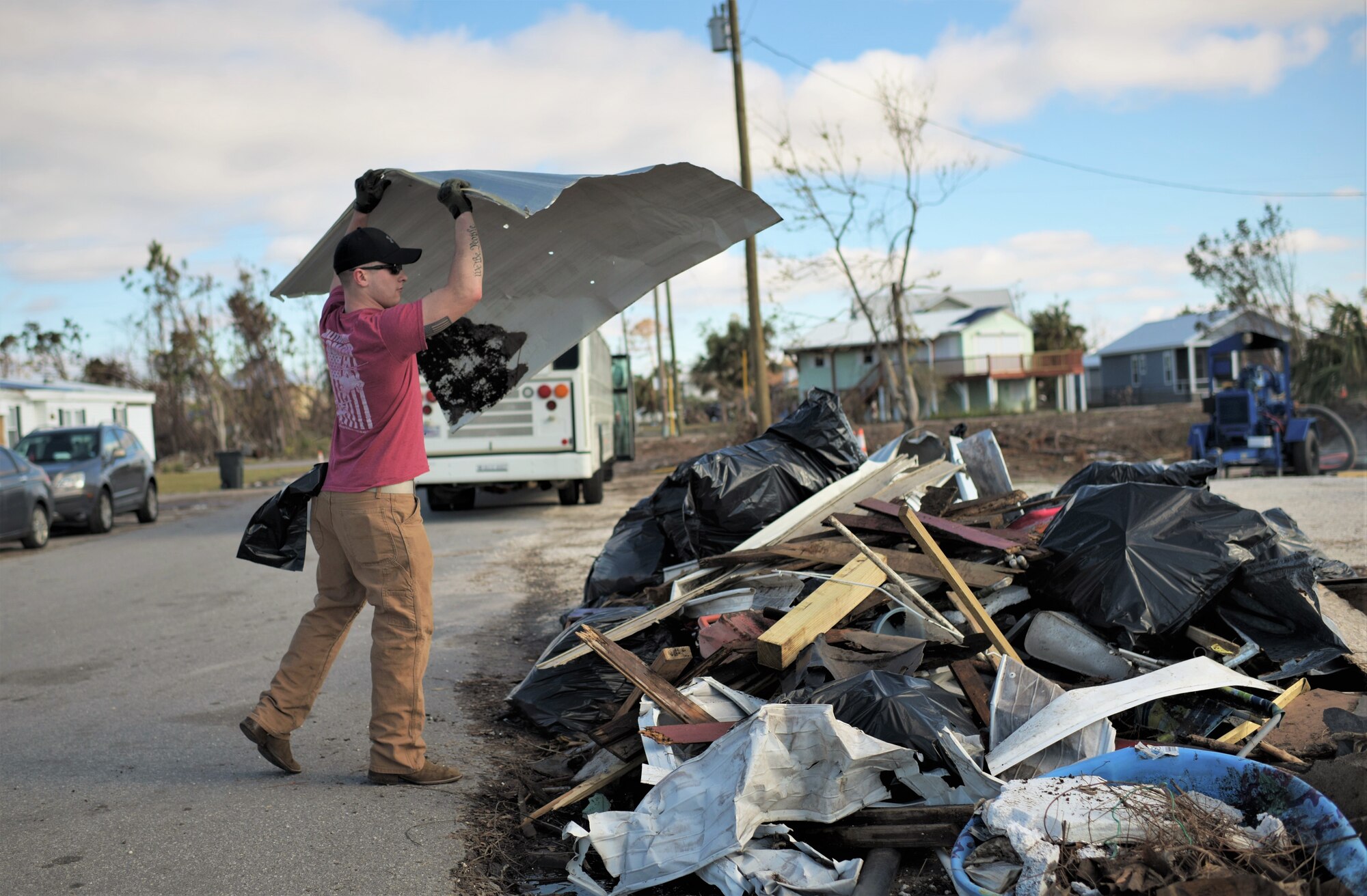 A volunteer from Tyndall Air Force Base throws paneling from a house into a pile of debris while cleaning Under the Palms Park in Mexico Beach, Fla., Dec. 16, 2018. Thirty nine volunteers from Tyndall and Eglin Air Force Bases came together to help clean of Mexico Beach, one of the communities hit the hardest by Hurricane Michael.  The volunteers were able to clean up more than 40 cubic yards of debris within four hours. (U.S. Air Force photo by Tech. Sgt. Sara Keller)