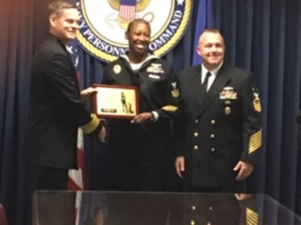Yeoman First Class Kealy R. Lee from Joint Base Charleston, S.C. is honored as the Bureau of Navy Personnel's Command Enterprise Sailor of the Year by Rear Adm. J.W. Hughes, left, and Force Master Chief Scott Rossiter, right, Nov. 12, 2018 in Millington, Tennessee. Lee will move on to compete at the next level for Military Personnel Training and Education Sailor of the Year at Pensacola, Florida.