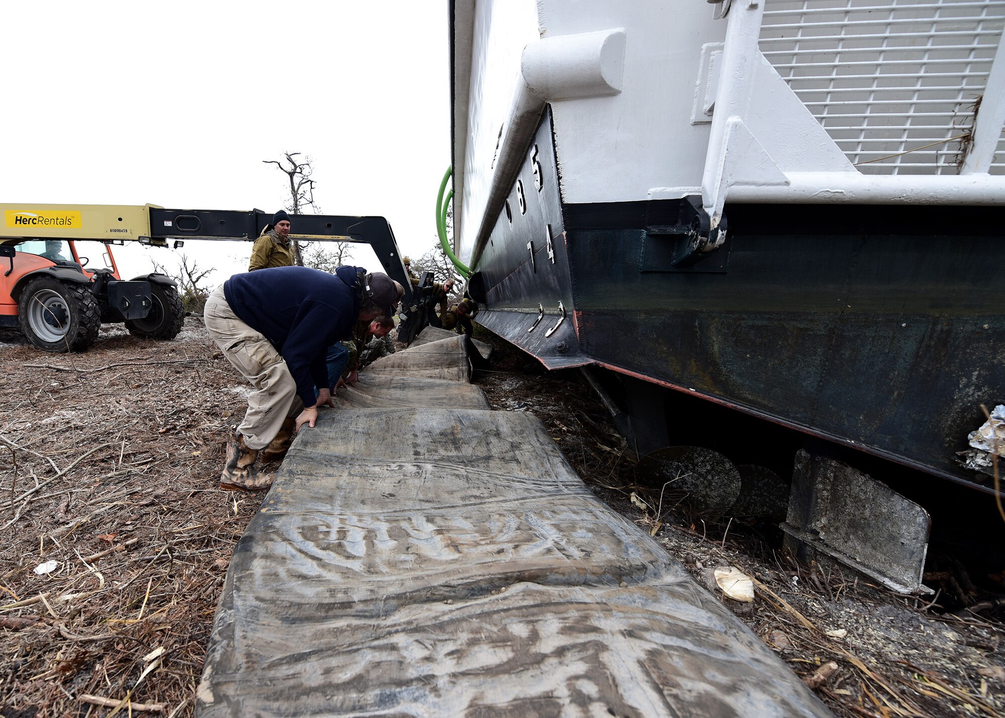 Airmen, Sailors and contractors push a large inflatable bladder beneath the hull of a beached U.S. Air Force Missile Retriever Ship near Tyndall Air Force Base, Fla., Dec. 13, 2018. The vessel ran aground during the powerful winds of Hurricane Michael. (U.S. Air Force photo by Senior Airman Isaiah J. Soliz)