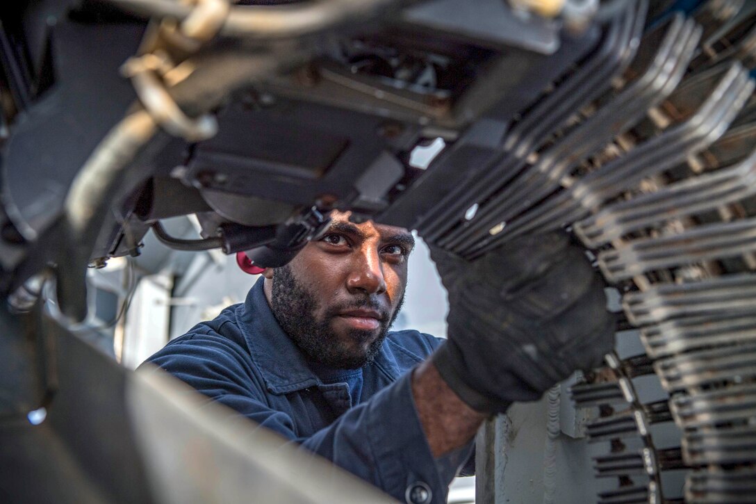 A sailor loads rounds into a large weapon.