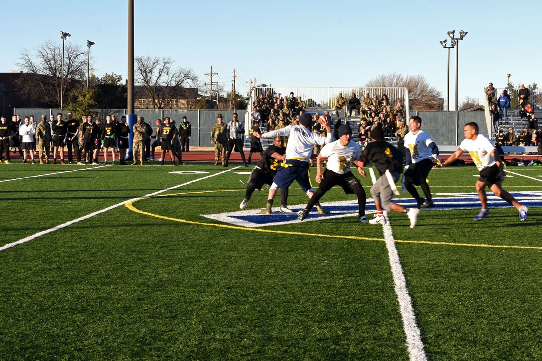 U.S. Navy Petty Officer 1st Class Cody Sykes, 312th Training Squadron fire instructor, avoids having his flag pulled, while trying to pass the ball, during the Army-Navy game at the Mathis Fitness Center field on Goodfellow Air Force Base, Texas, Dec. 14, 2018. The Army defeated the Navy with a final score of 13-7. (U.S. Air Force photo by Airman 1st Class Zachary Chapman/Released)