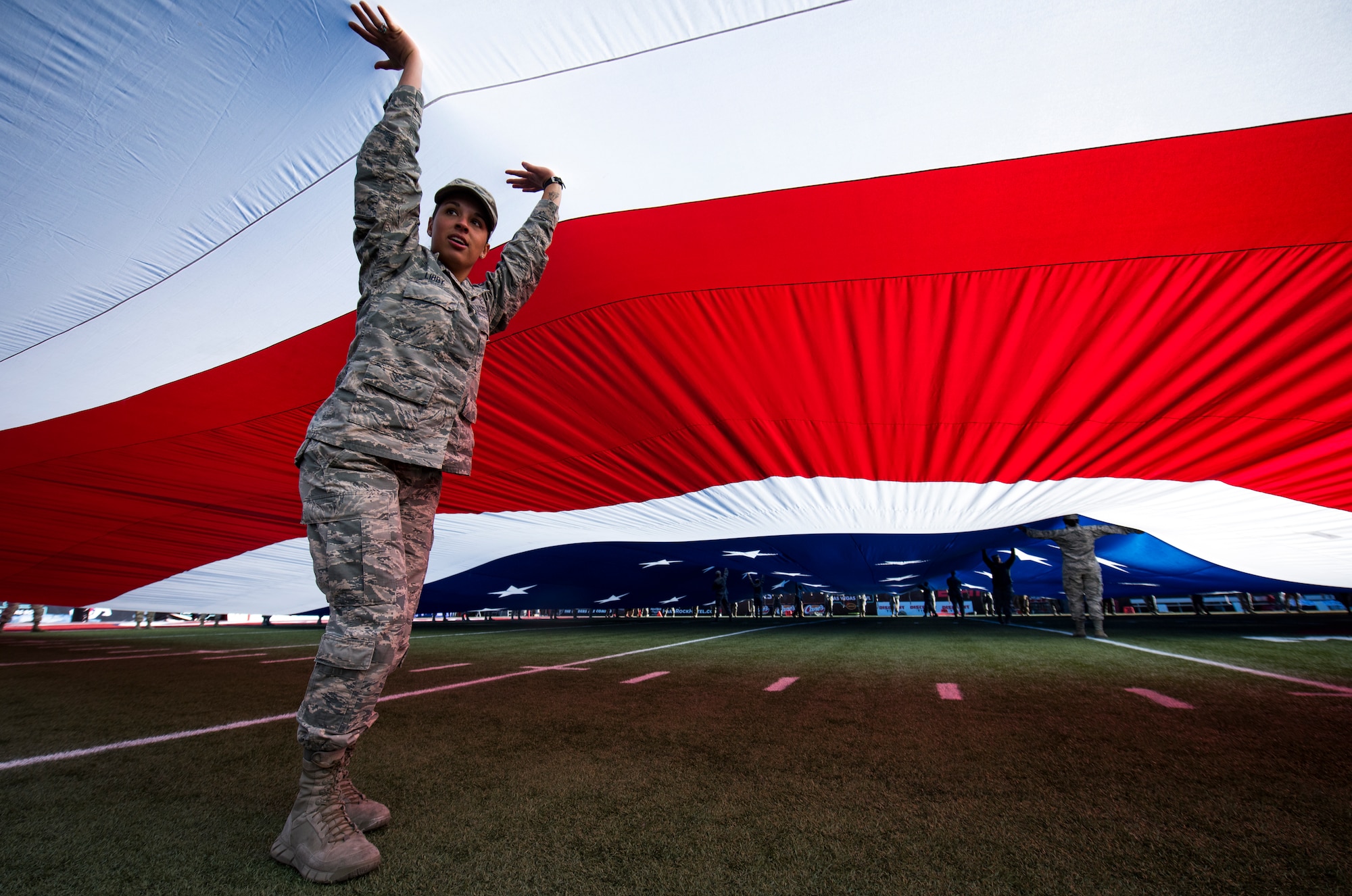 Airman 1st Class Ashley Libby, an aerospace medical technician assigned to the 99th Medical Operations Squadron at Nellis Air Force Base, Nevada, holds up a section of a half-ton American flag during the 2018 Las Vegas Bowl opening ceremony at Sam Boyd Stadium in Las Vegas, Dec. 15, 2018. More than 200 Airmen volunteered to carry the flag. (U.S. Air Force photo by Senior Airman Andrew D. Sarver)