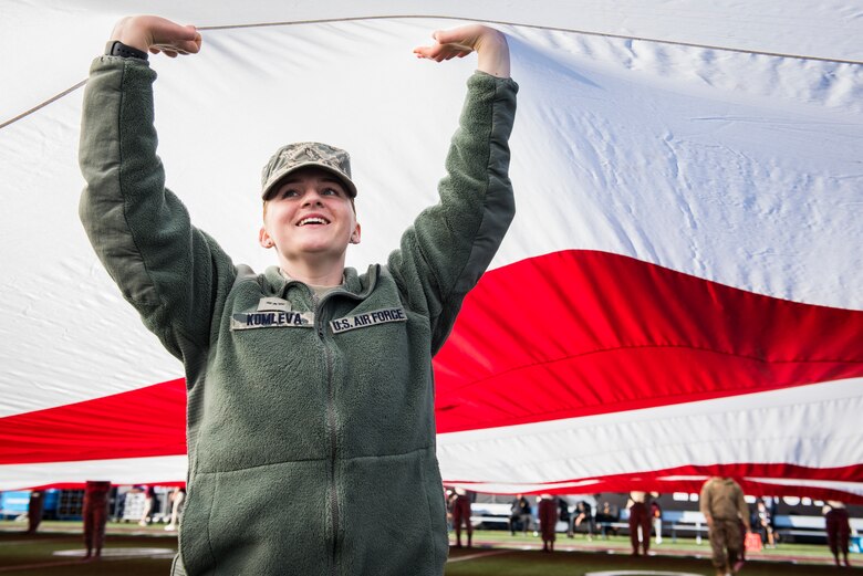 Airman 1st Class Lolita Komleva, a pharmacy technician assigned to the 99th Medical Operations Squadron at Nellis Air Force Base, Nevada, lifts her arms to help keep a half-ton American flag off the ground during the 2018 Las Vegas Bowl opening ceremony at Sam Boyd Stadium in Las Vegas, Dec. 15, 2018. Komleva was one of more than 200 Airmen who volunteered to carry the giant flag. (U.S. Air Force photo by Senior Airman Andrew D. Sarver)