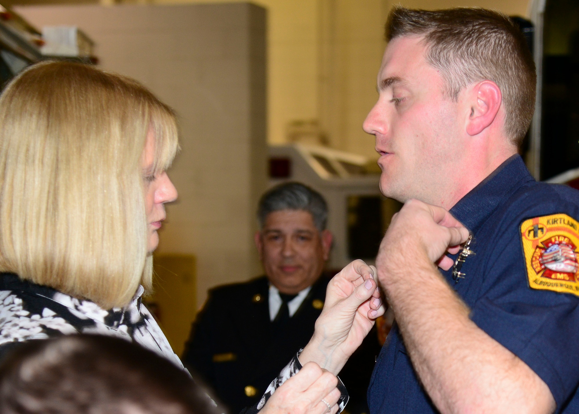 Lynda Davis pins her son Christopher Davis during the Kirtland AFB Fire and Emergency Services Training Academy graduation here Dec. 14. The graduates underwent eight weeks of training completing the first iteration conducted at Kirtland for 14 years. (U.S. Air Force photo by Jessie Perkins)