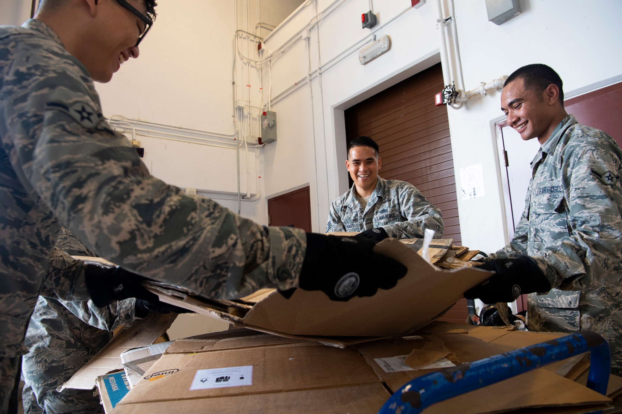 U.S. Air Force Airman Willy Hong (left to right), Staff Sgt. Michael Penaso and Airman Brandon Phillip, all air transportation specialist with the U.S. Air Force Reserve’s 44th Aerial Port Squadron, break down empty donation boxes Dec. 8, 2018, during Operation Christmas Drop at Andersen Air Force Base, Guam. Operation Christmas Drop is a U.S. Air Force-led trilateral training event that includes air support from the Japanese Air Self Defense Force and Royal Australian Air Force to airdrop supplies to the Commonwealth of the Northern Marianas, Federated States of Micronesia, and the Republic of Palau. (U.S. Air Force photo by Jerry R. Bynum)