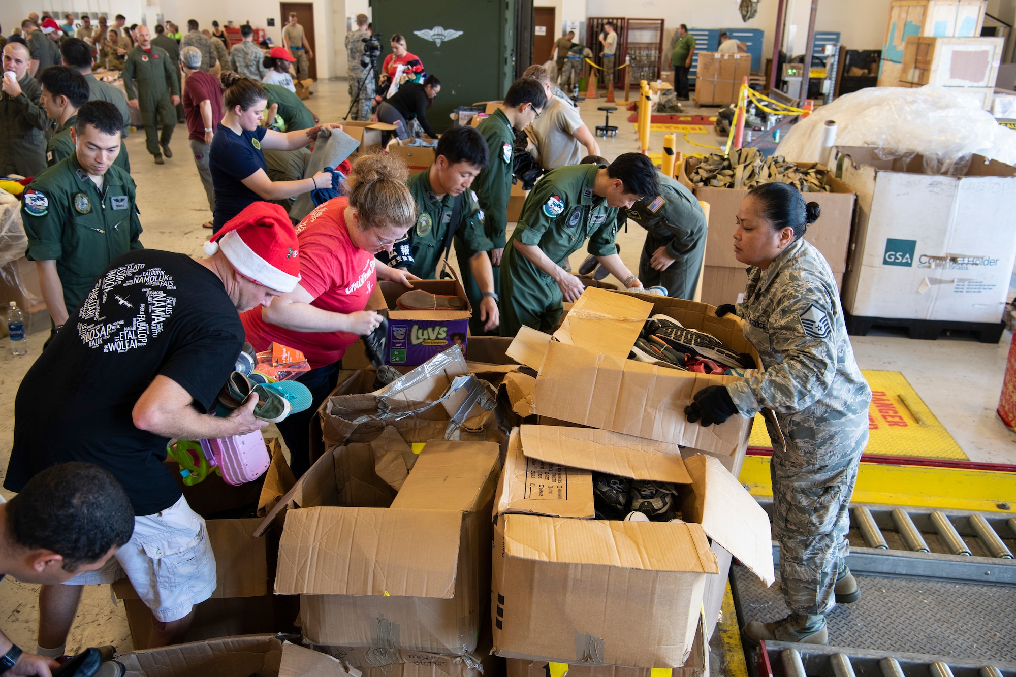 U.S. Air Force Master Sgt. Eileen Quichocho, an air transportation specialist with the U.S. Air Force Reserve’s 44th Aerial Port Squadron, stacks donations for volunteers to pack into airdrop bundles Dec. 8, 2018, during Operation Christmas Drop at Andersen Air Force Base, Guam. Operation Christmas Drop is a U.S. Air Force-led trilateral training event that includes air support from the Japanese Air Self Defense Force and Royal Australian Air Force to airdrop supplies to the Commonwealth of the Northern Marianas, Federated States of Micronesia, and the Republic of Palau. (U.S. Air Force photo by Jerry R. Bynum)