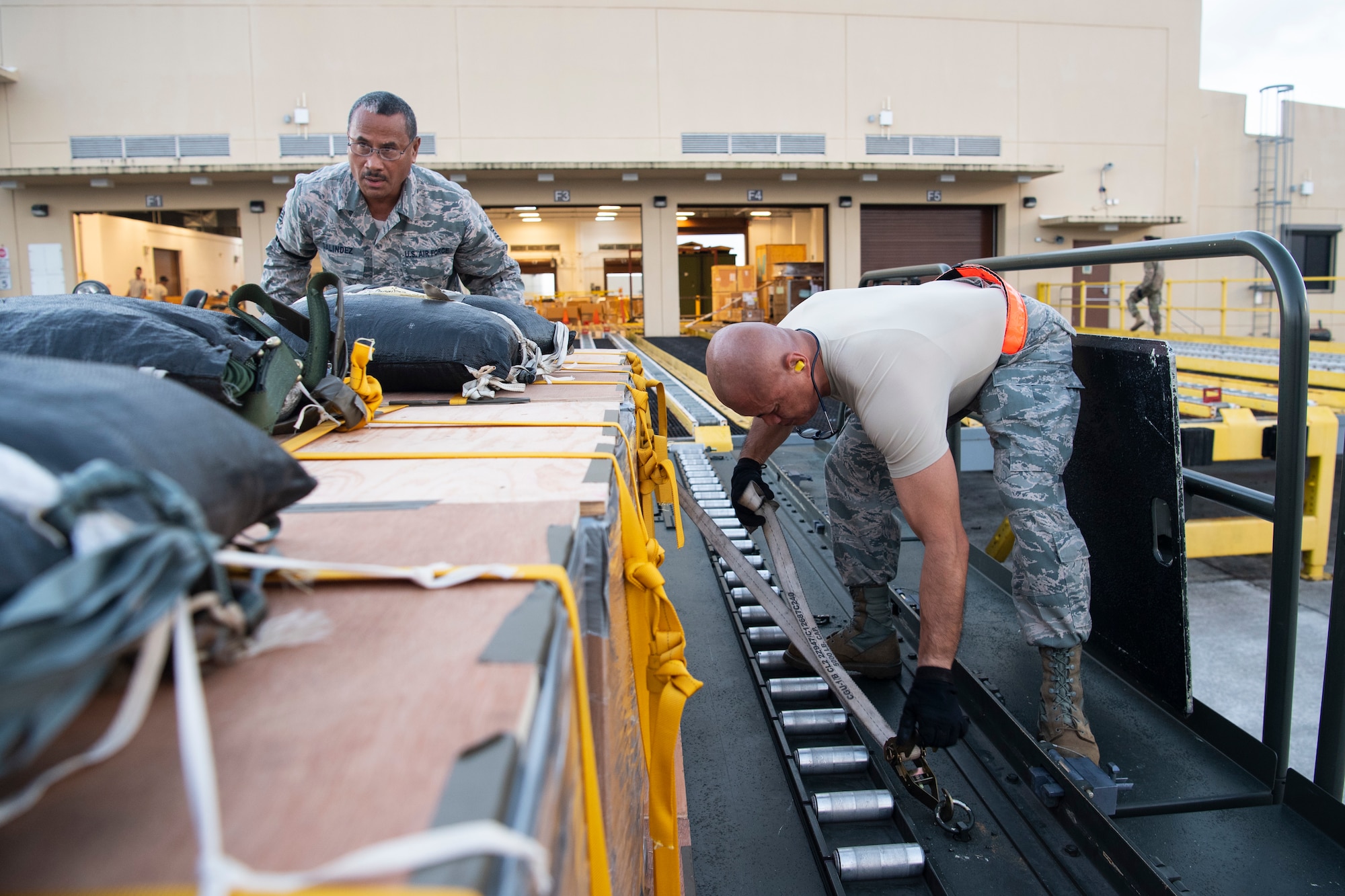 U.S. Air Force Tech. Sgt. Sinforoso Galindez (left to right) and Master Sgt. Angel Llagas, both air transportation specialist with the U.S. Air Force Reserve’s 44th Aerial Port Squadron, secure airdrop bundles onto a Tunner 60K aircraft loader for transportation out to awaiting aircraft Dec 9, 2018, during Operation Christmas Drop at Andersen Air Force Base, Guam. Operation Christmas Drop is a U.S. Air Force-led trilateral training event that includes air support from the Japanese Air Self Defense Force and Royal Australian Air Force to airdrop supplies to the Commonwealth of the Northern Marianas, Federated States of Micronesia, and the Republic of Palau. (U.S. Air Force photo by Jerry R. Bynum)