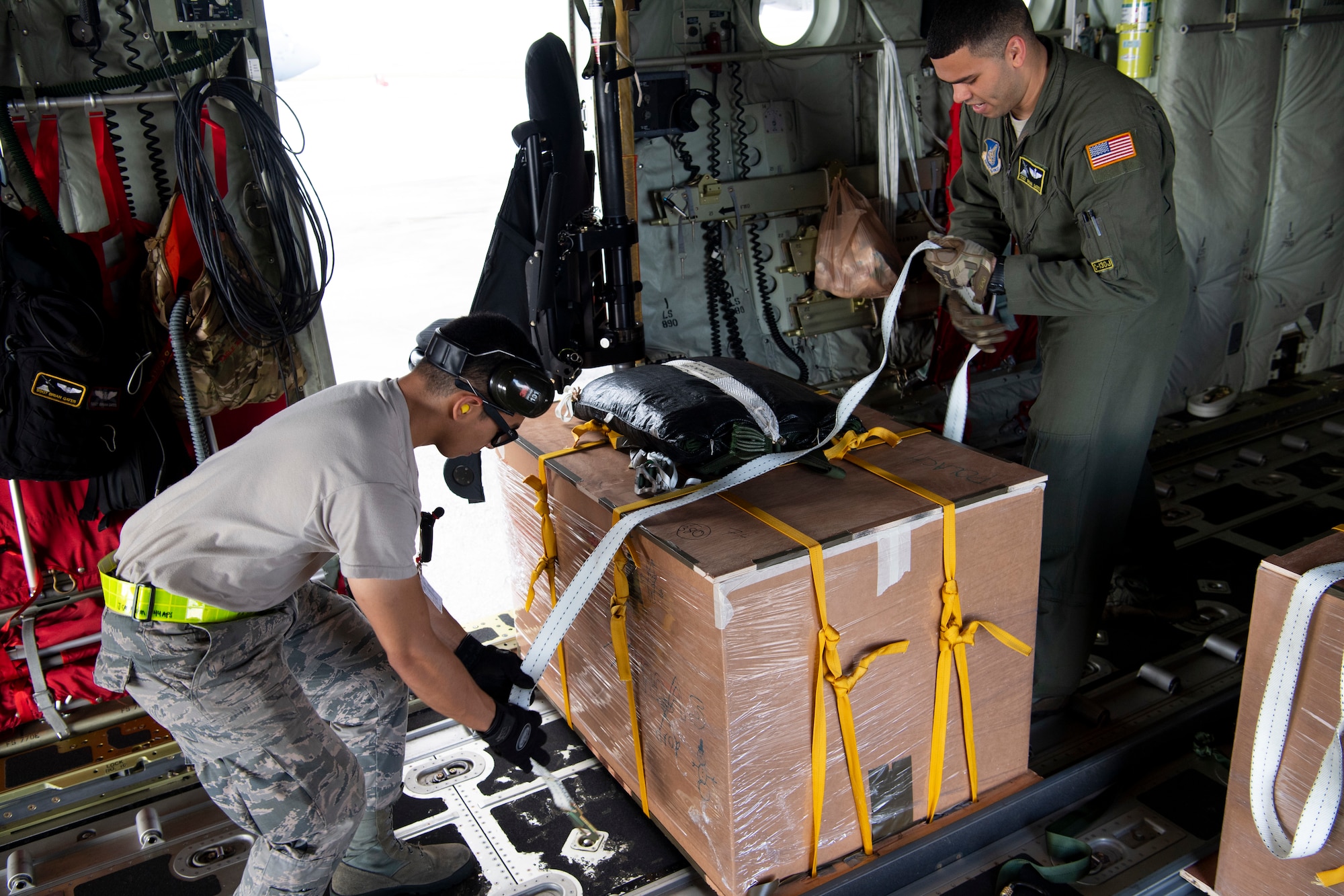 U.S. Air Force Airman 1st Class Joshua San Agustin (left to right), an air transportation specialist with the U.S. Air Force Reserve’s 44th Aerial Port Squadron, and Staff Sgt. Brian Gates, a loadmaster with the 374th Airlift Wing at Yokota Air Base, Japan, load a U.S. Air Force C-130J Hercules Dec. 11, 2018, with an airdrop bundle during Operation Christmas Drop at Andersen Air Force Base, Guam. Operation Christmas Drop is a U.S. Air Force-led trilateral training event that includes air support from the Japanese Air Self Defense Force and Royal Australian Air Force to airdrop supplies to the Commonwealth of the Northern Marianas, Federated States of Micronesia, and the Republic of Palau. (U.S. Air Force photo by Jerry R. Bynum)