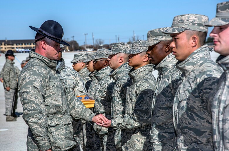 Military Training Instructor Tech. Sgt. Prentiss Carver, 433rd Training Squadron Reserve Citizen Airman, presents the Airman’s coin to one of his trainees during the Dec. 13 Airman’s coin presentation ceremony at Joint Base San Antonio-Lackland. The ceremony occurs the day before basic military training graduation and symbolizes that the trainee has completed BMT requirements and has earned the right to be called Airman. (U.S. Air Force photo by Johnny Saldivar)