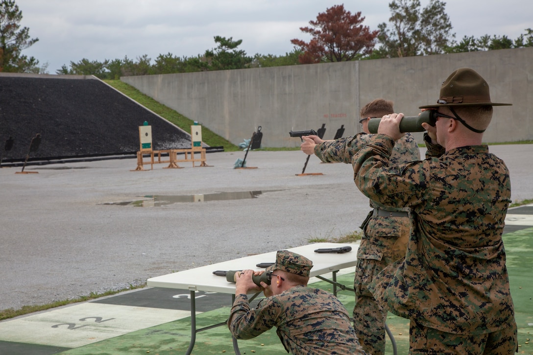 A U.S. Marine shooter and spotters assess the target in the Team Pistol Match finals at Range 1 on Camp Hansen Dec. 13, 2018. Marine Corps Shooting Teams members verified the hits of the shooter.