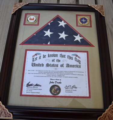 John E. Drake received a framed photo and the American Flag that was flown at the Bagram Airfield over the USACE Afghanistan District Headquarters. The flag represents the will and resolve of the American people to protect those who cannot protect themselves; to stand strong and defeat all who attempt to bring America Harm.
