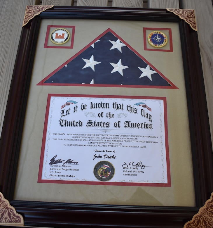 John E. Drake received a framed photo and the American Flag that was flown at the Bagram Airfield over the USACE Afghanistan District Headquarters. The flag represents the will and resolve of the American people to protect those who cannot protect themselves; to stand strong and defeat all who attempt to bring America Harm.