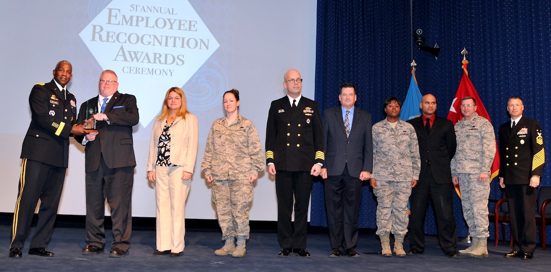 DLA Director and DLA Navy Senior Enlisted Leader present a group award to a team of eight people.