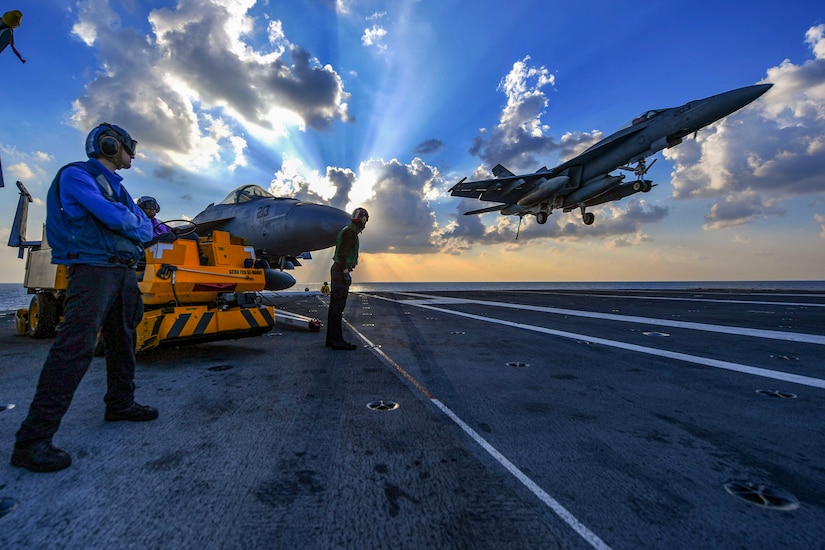 An aircraft comes in for a landing on the flight deck of a navy vessel.