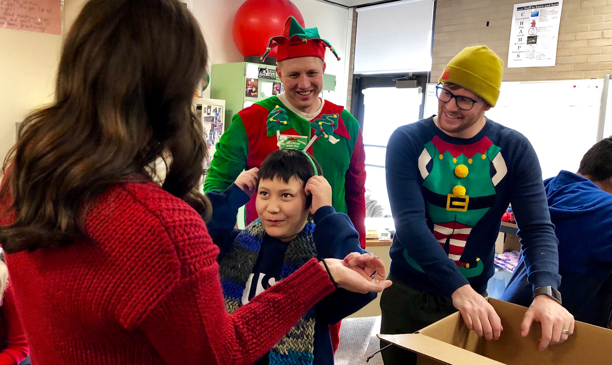 Tech. Sgt. Brad Williams and Senior Airman Todd Rimmach act as Santa’s helpers to Shaylan during a Christmas party at Mound Fort Junior High in Ogden