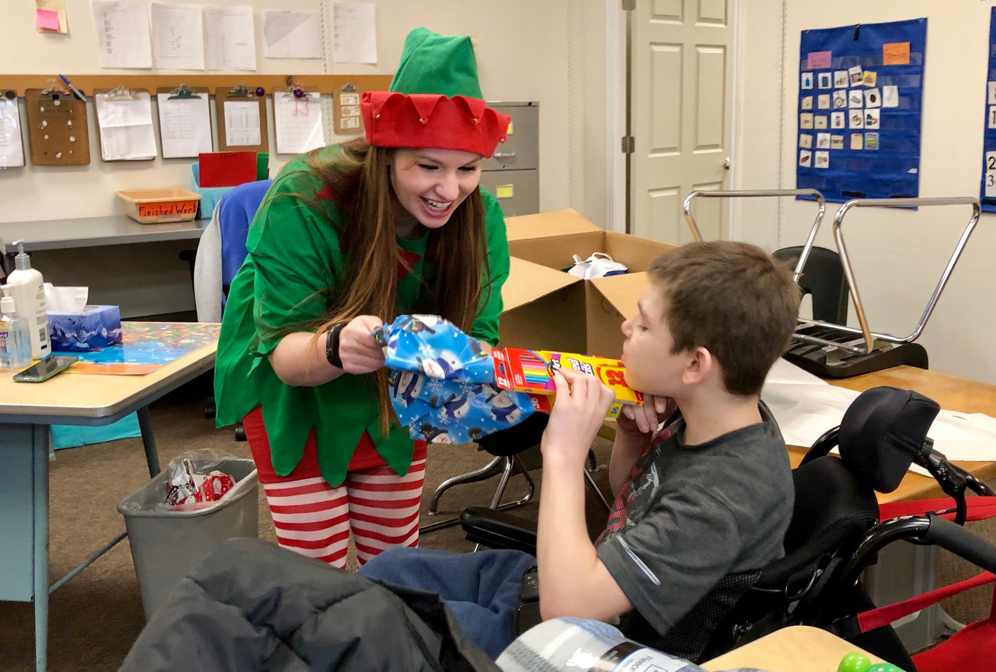 Senior Airman Amy Barnes, 67th Aerial Port Squadron, helps Andrew unwrap gifts during a Christmas party at Mound Fort Junior High in Ogden