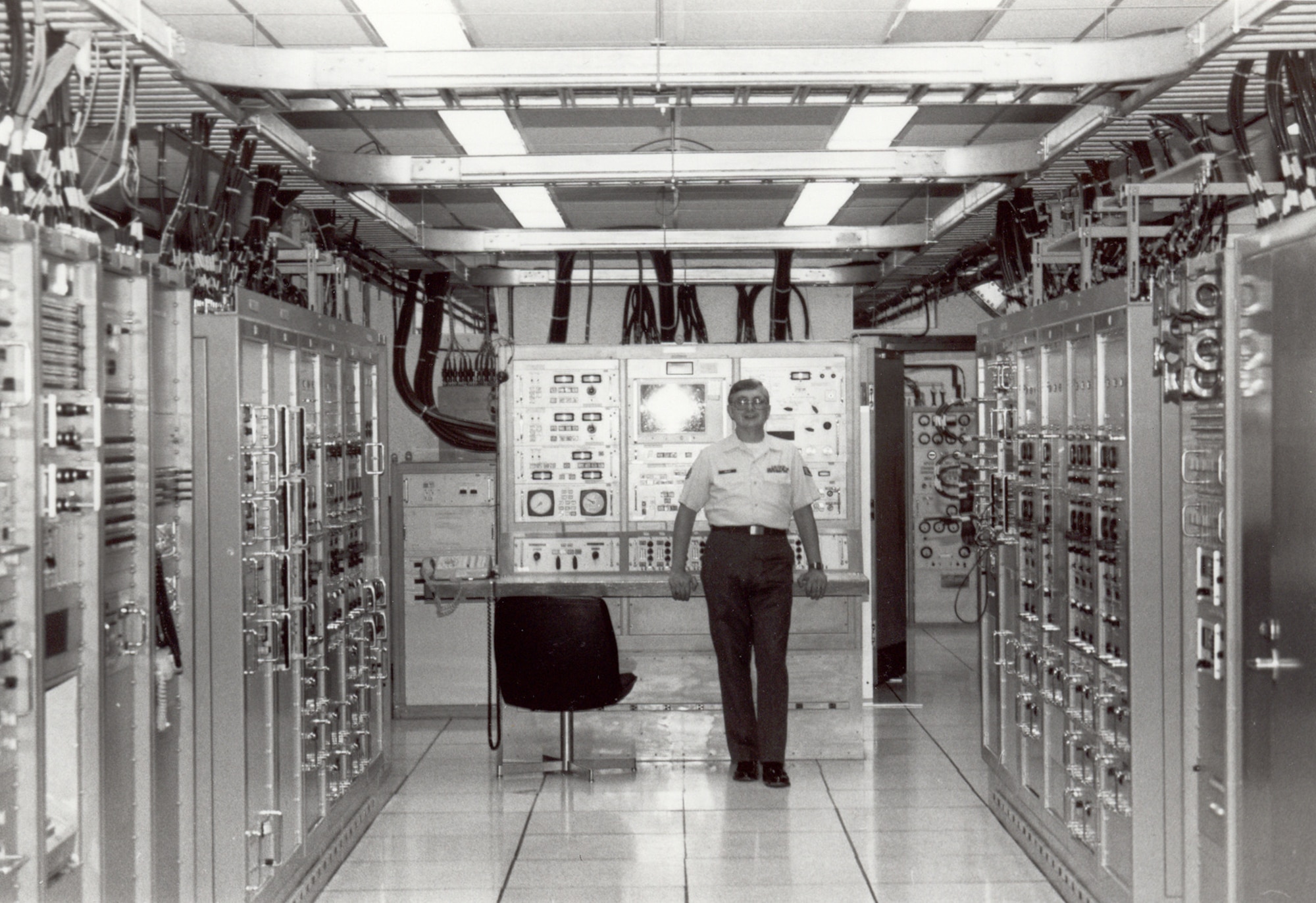 A member of the 1st Aerospace Communications Group stands among the equipment racks of the Defense Satellite Communications System terminal collocated with the AFSATCOM consolidated ground terminal, Offutt AFB, Nebraska, 5 Jun 1981.