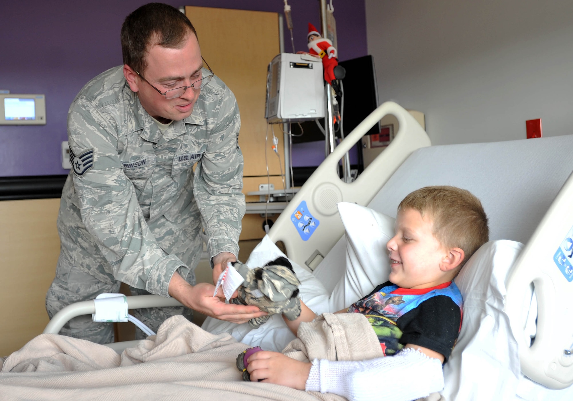 Staff Sgt. Jeremy Robinson, 373rd Training Squadron, Det. 8 KC-46 Pegasus and KC-135 Stratotanker hydraulic instructor, hands a military teddy bear to a child Dec. 18, 2018, at Wesley Children’s Hospital. The members wanted to spread some cheer to children right before the holidays to brighten their mood and make the stay at the hospital a little better. (U.S. Air Force photo by Staff Sgt. David Bernal Del Agua)
