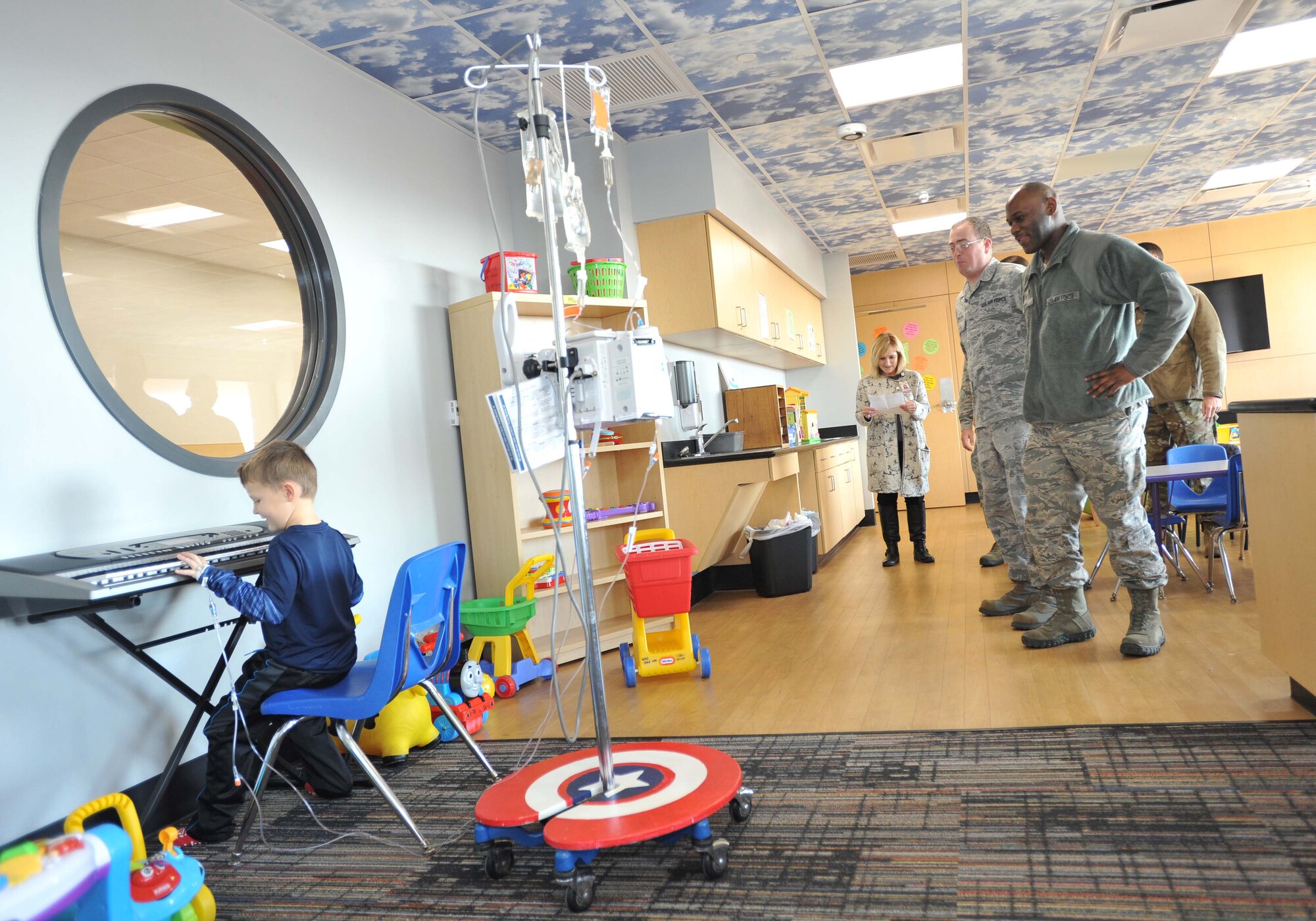 Tech. Sgt. Quadarris Fitts, 373rd Training Squadron, Det. 8 KC-46 Pegasus systems instructor, and Staff Sgt. Jeremy Robinson, 373rd TRS, Det. 8 KC-46 Pegasus and KC-135 Stratotanker hydraulic instructor, watch as a child plays the piano Dec. 18, 2018, at Wesley Children’s Hospital. The Airmen took a break from distributing toys to stop and enjoy a little concert by one of the children in the general medicine ward. (U.S. Air Force photo by Staff Sgt. David Bernal Del Agua)