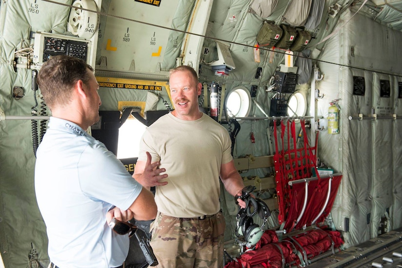 An airman talks with a golfer inside a C-130.
