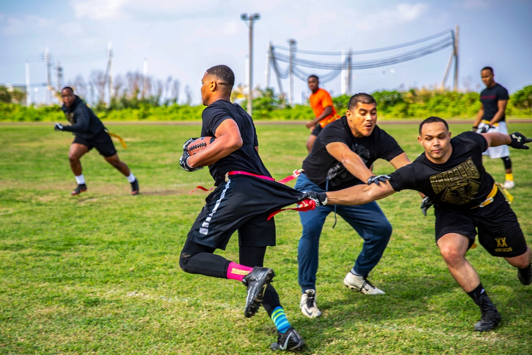 Lance Cpl. Artanza Starr runs to avoid defenders during a flag football game at the fourth annual Reindeer Games on Camp Kinser, Okinawa, Japan, Dec. 18, 2018. The Reindeer Games are a holiday-themed, family event held to boost morale and camaraderie among the Marines, Sailors and families of Combat Logistics Regiment 37, 3rd Marine Logistics Group. Starr, an administration clerk with Headquarters Company, CLR-37, 3rd MLG, is a native of Bossier, Louisiana. (U.S. Marine Corps photo by Cpl. Joshua Pinkney)