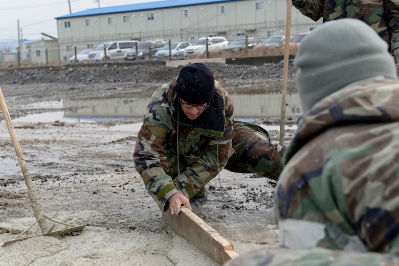 U.S. Air Force Staff Sgt. Travis Lowe, 8th Civil Engineer Squadron pavement and equipment operator, levels a section of wet concrete during Rapid Airfield Damage Repair training at Kunsan Air Base, Republic of Korea, Dec. 6, 2018. Maintaining a high level of proficiency in working with quick drying concrete is one critical aspect of being able to quickly repair damage to the airfield under different conditions. (U.S. Air Force photo by 1st Lt. Madeline Krpan)