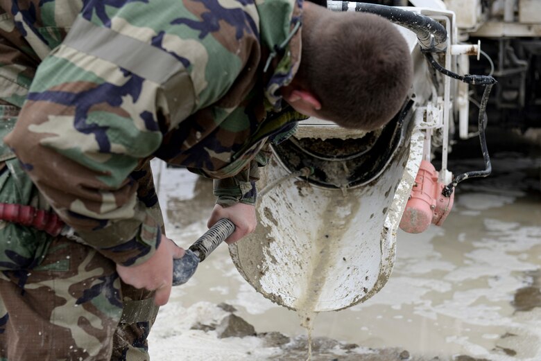 U.S Air Force Staff Sgt. Clifford Marcus, 8th Civil Engineer Squadron pavement and equipment operator, pressure washes the inside of an auger and concrete shoot from a volumetric mixer at Kunsan Air Base, Republic of Korea, Dec. 6, 2018. Maintaining a high level of proficiency in working with quick drying concrete is one critical aspect of being able to repair airfield damage under different conditions. (U.S. Air Force photo by 1st Lt. Madeline Krpan)