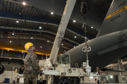 Tech. Sgt. Alejo Blas, 8th Expeditionary Aircraft Maintenance Squadron (EAMS)  lead technical crew chief, helps guide the lifting of a pitch trim actuator with the help of Airmen of the 379th Expeditionary Civil Engineer Squadron (ECES), during a removal, repair and replacement procedure Dec. 18, 2018, at Al Udeid Air Base, Qatar. This is the first time a maintenance procedure like this has been done in U.S. Air Forces Central Command’s area of responsibility. Due to safety concerns, Airmen from the 8th EAMS and 379th ECES combined capabilities to ensure the aircraft could be repaired prior to returning to home station. (U.S. Air Force photo by Tech. Sgt. Christopher Hubenthal)